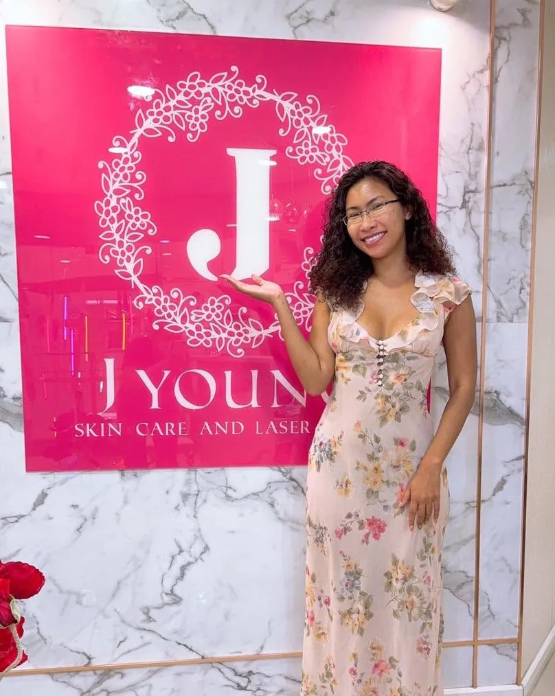 ลูกค้าถ่ายภาพที่ระลึกข้างป้าย J Young Clinic สวมชุดเดรสลายดอกไม้