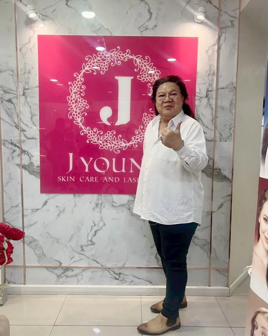 ลูกค้าถ่ายภาพที่ระลึกข้างป้าย J Young Clinic สวมเสื้อเชิ้ตสีขาว