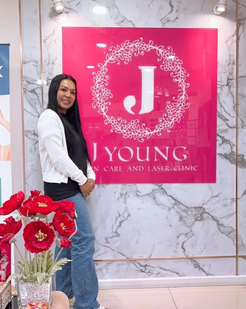 ลูกค้าถ่ายภาพที่ระลึกข้างป้าย J Young Clinic สวมเสื้อคลุมสีขาว